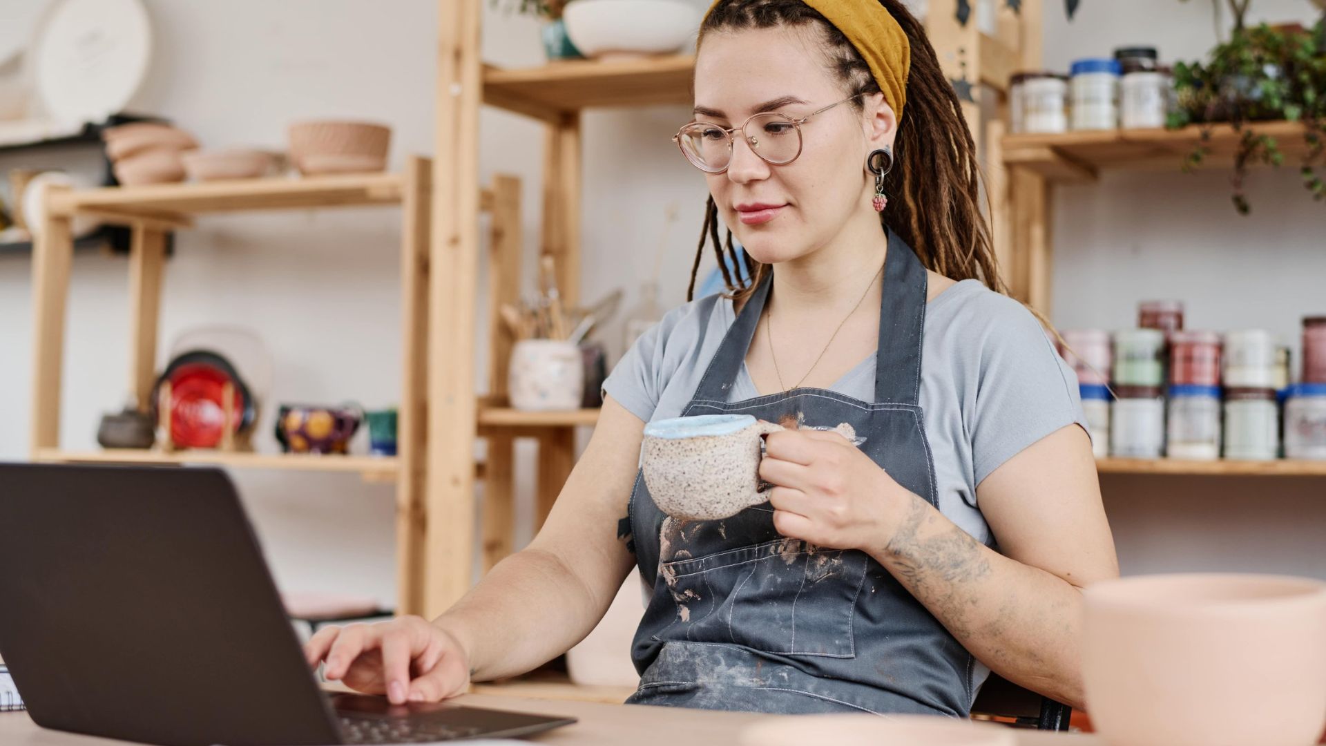 A Business Owner in her office drinking tea using a laptop